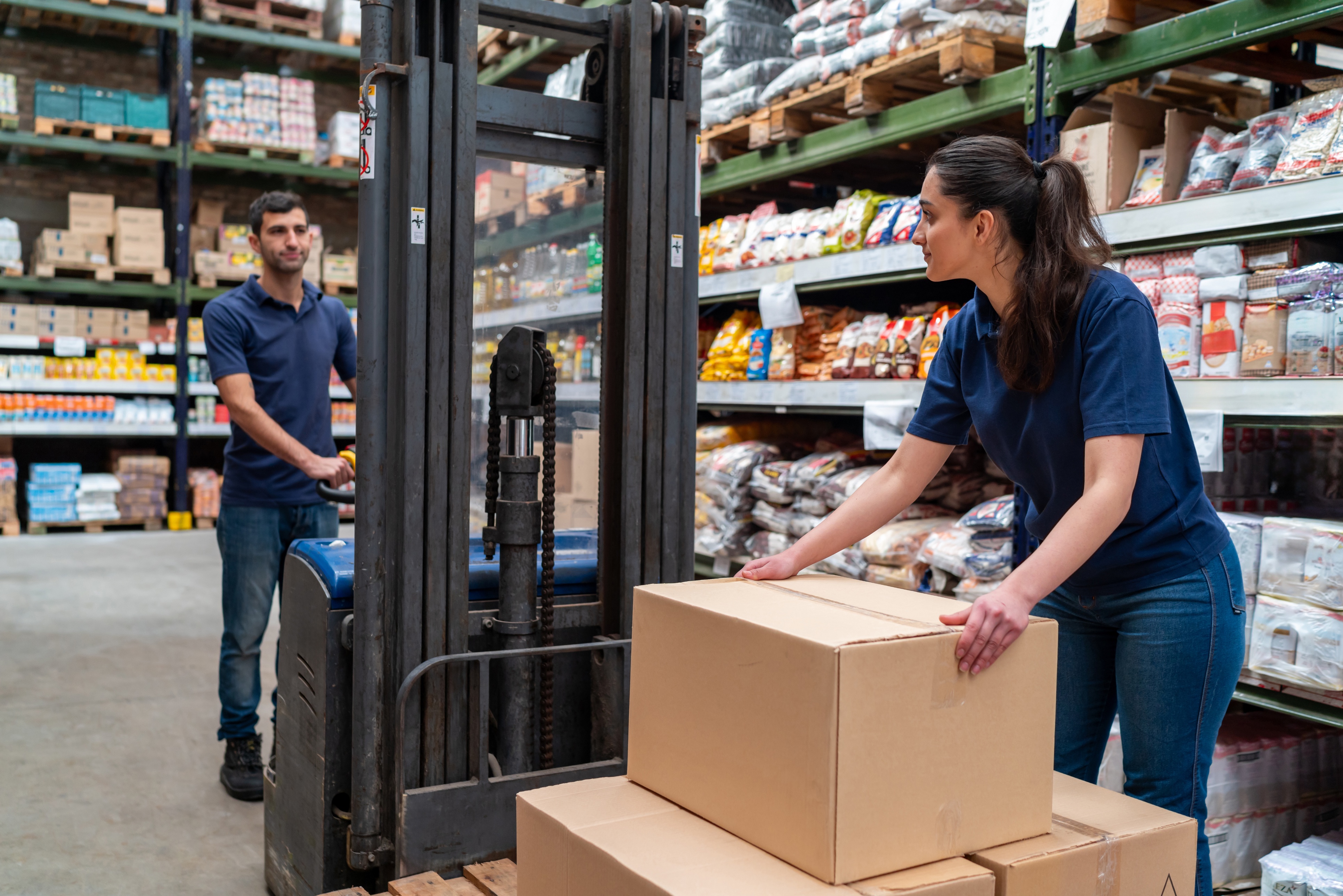 Warehouse workers collaborating with boxes and forklift
